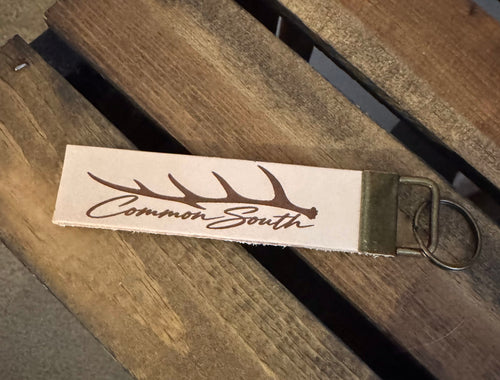 Common South leather keychain engraved with an antler and script logo